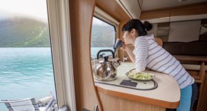 Woman looking out RV window at lake